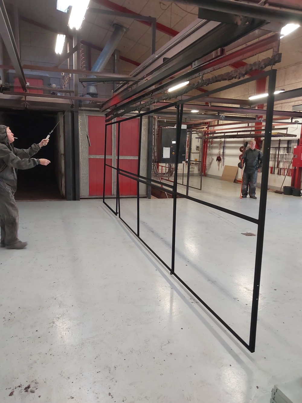 Personer arbejder med sorte rammer efter pulverlakering i produktionsområde